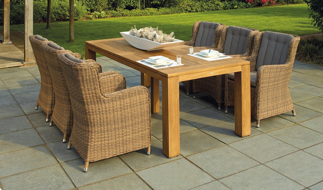 services-01 A serene outdoor patio set up with rattan chairs and a wooden table, perfect for relaxation.